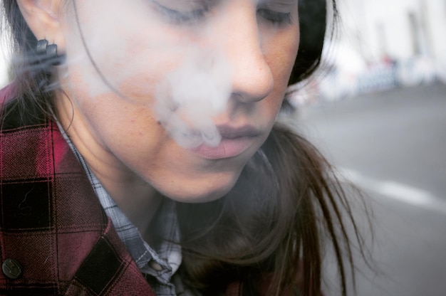 Photo close-up of young woman exhaling smoke