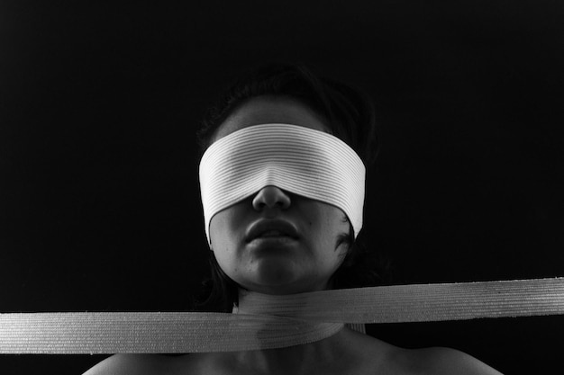 Photo close-up of young woman eyes covered with bandage against black background