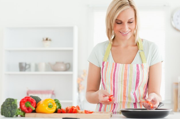 Chiuda in su di una giovane donna che frigge i peperoni