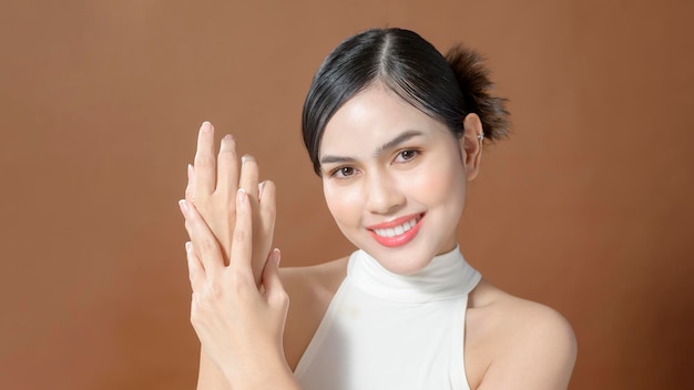 Close up young woman hand is applying cream over brown background beauty skin care concept