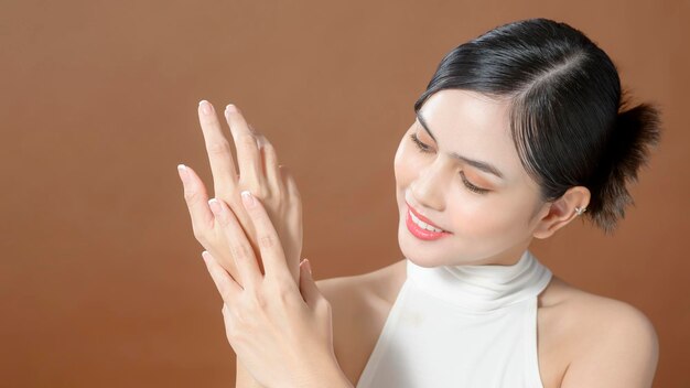 Close up young woman hand is applying cream over brown background beauty skin care concept