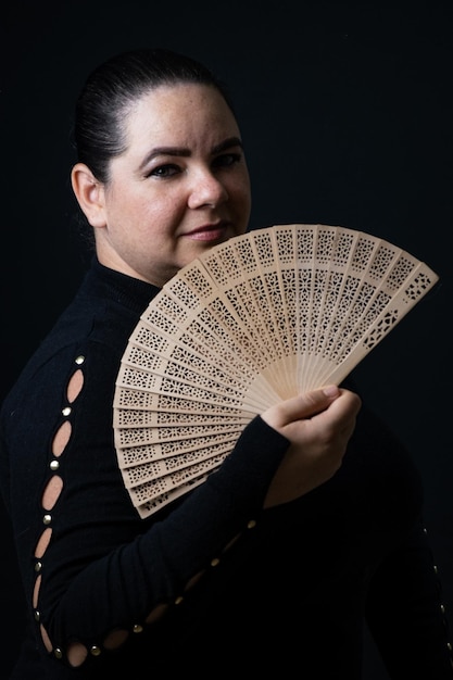 Close-up of young woman handing fan against black background