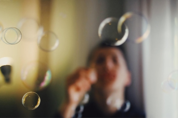 Photo close-up of young woman holding curtain at home