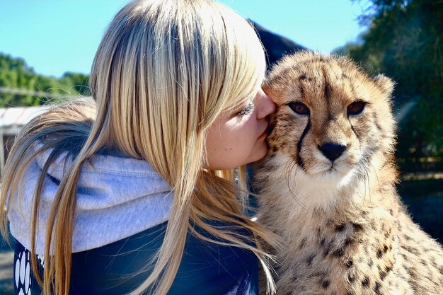 Photo close-up of young woman kissing cheetah