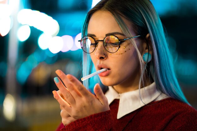 Foto close-up di una giovane donna che accende una sigaretta