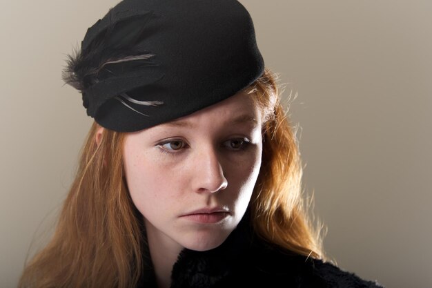 Photo close-up of young woman looking away against wall