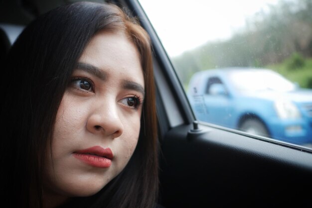 Photo close-up of young woman looking away in car