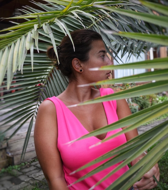 Photo close-up of young woman looking away while standing by plant outdoors