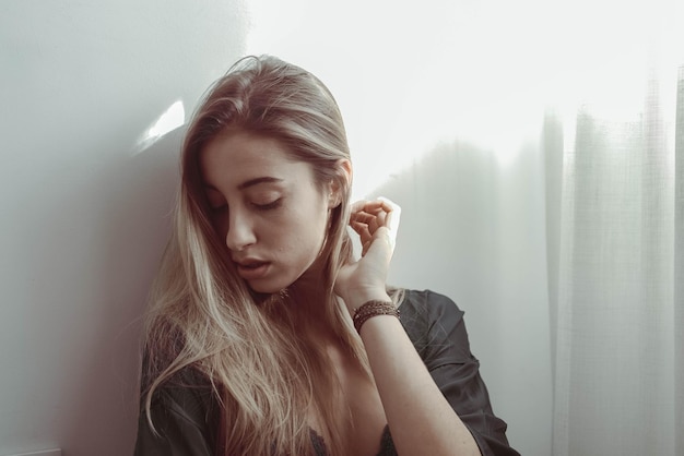 壁に向かって下を見下ろす若い女性のクローズアップ