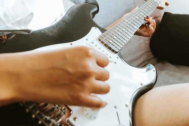 Foto primo piano di un paio di mani di giovane donna che suonano una chitarra all'aperto. giornata di sole e pratica di un concetto di strumento. copia spazio musica vita in tour e natura.