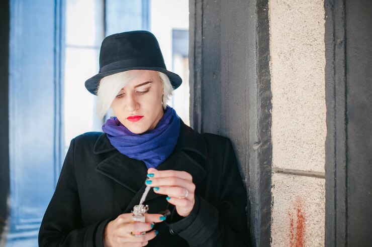 Photo close-up of young woman preparing electronic cigarette by column
