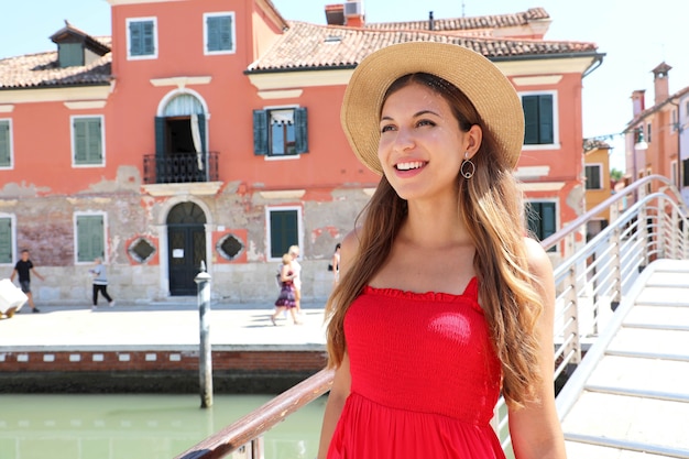 Foto close up della giovane donna in abito rosso camminando sul ponte nel villaggio di burano, venezia, italia