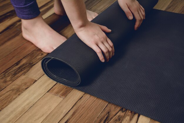 Close-up of young woman rolling her fitness mat