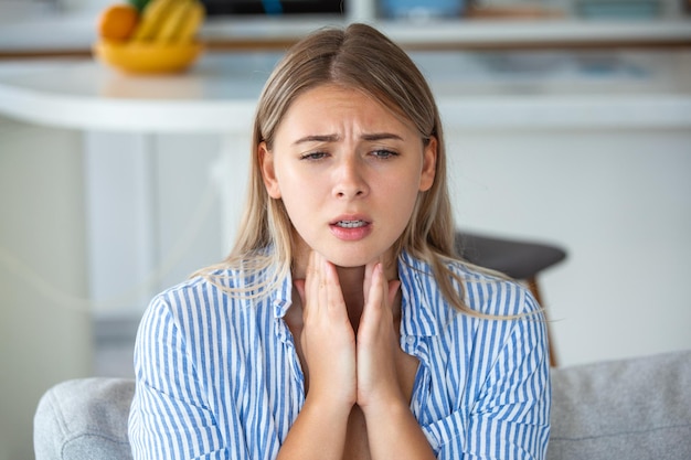 Photo close up of young woman rubbing her inflamed tonsils tonsilitis problem cropped woman with thyroid gland problem touching her neck girl has a sore throat