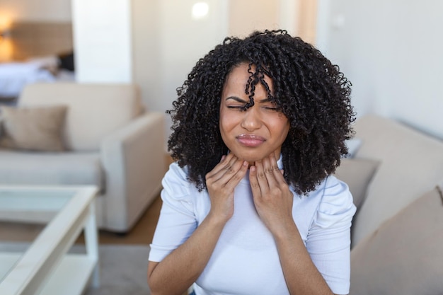 Close up of young woman rubbing her inflamed tonsils tonsilitis problem cropped Woman with thyroid gland problem touching her neck girl has a sore throat