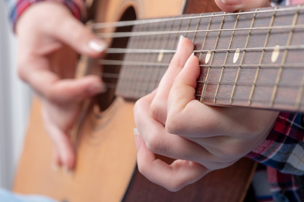 Primo piano delle mani di una giovane donna a suonare la chitarra