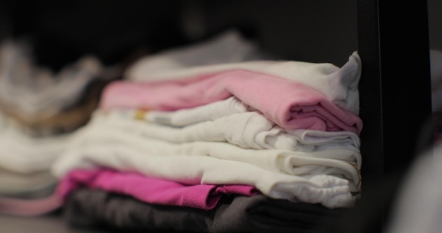 Photo close up young woman selects clothes from a neatly folded pile of home wardrobe search for the right clothes