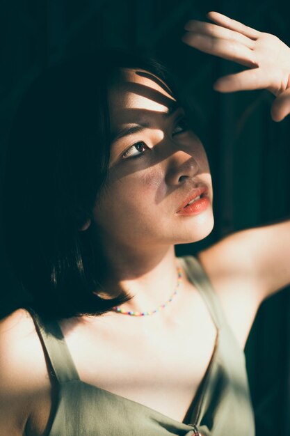 Photo close-up of young woman shielding eyes while standing at home