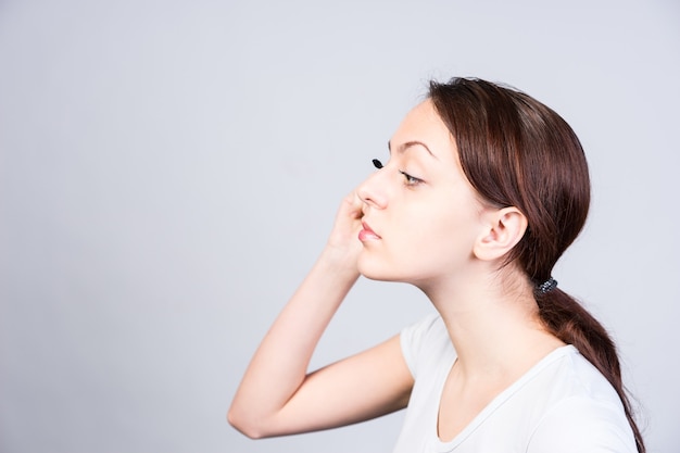 Close up Young Woman in Side View Applying Mascara Makeup While Looking to the Left of the Frame.