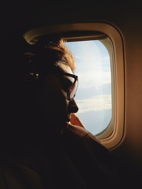 Photo close-up of young woman sleeping by window in airplane