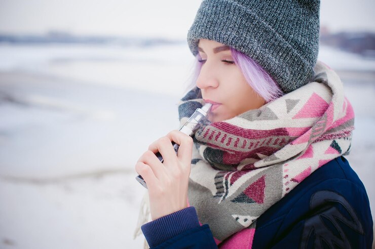 Photo close-up of young woman smoking while standing on snow
