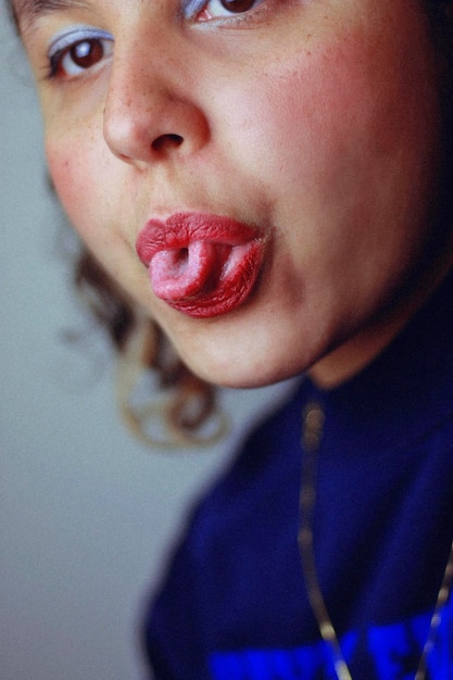 Photo close-up of young woman sticking out tongue