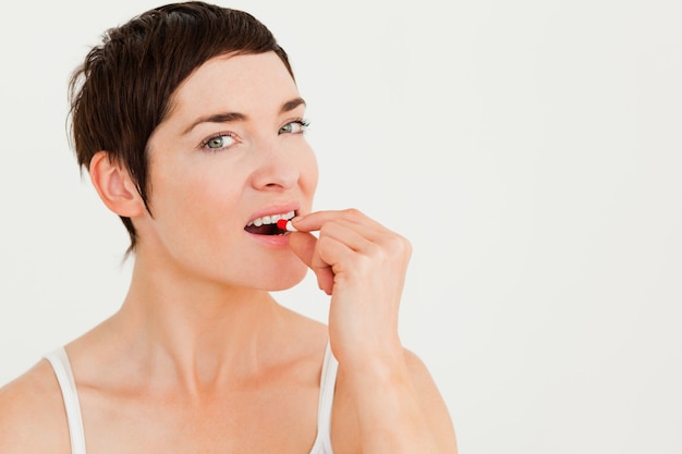 Photo close up of a young woman taking a pill