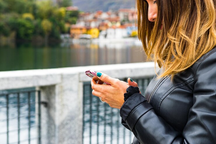 Photo close-up of young woman using phone against lake