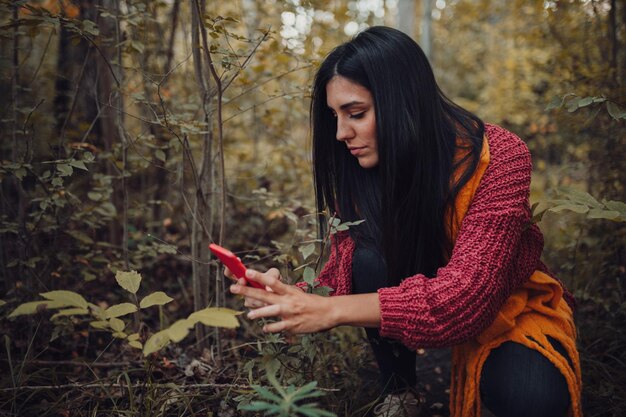 Photo close-up of young woman using smart phone in forest