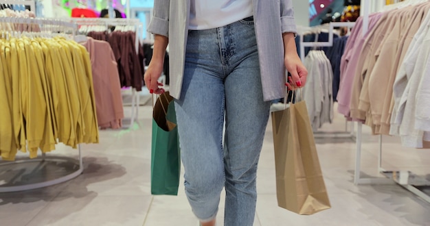 Close up of young woman walks with colorful shopping bags around a department store. Shopping after quarantine.