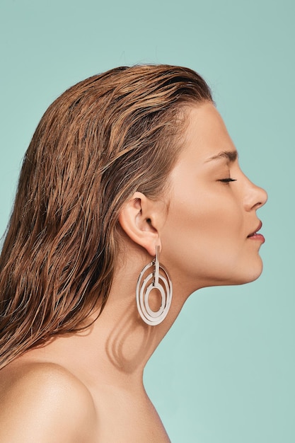 Photo close-up of young woman wearing earring against blue background