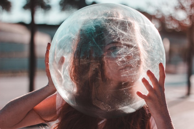 Photo close-up of young woman wearing glass container outdoors