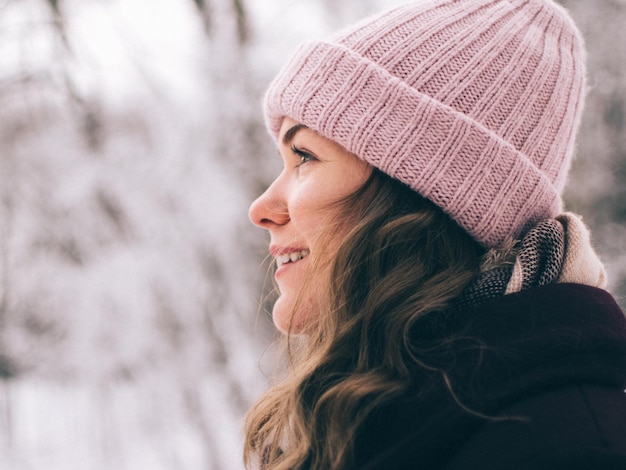 close-up of young woman wearing knit hat looking away