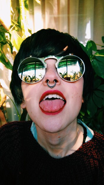 Close-up of young woman wearing sunglasses sticking out tongue