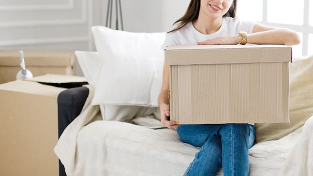 Avvicinamento. giovane donna con una scatola di cartone seduta sul divano nel nuovo soggiorno