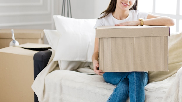 Close up. young woman with a cardboard box sitting on the sofa in the new living room