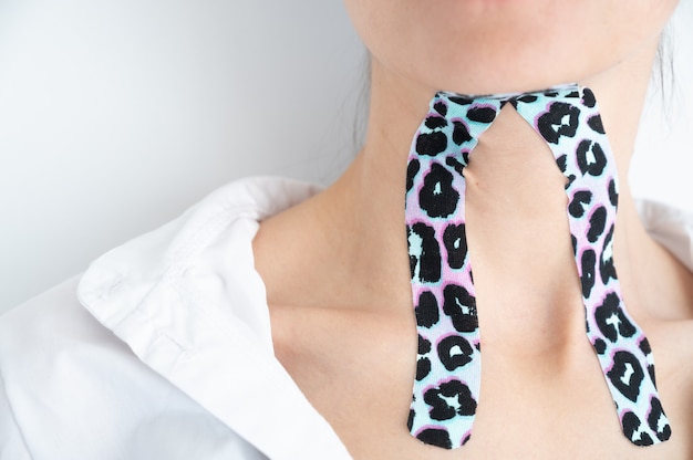 Photo close-up of young woman with colorful tapes on neck.aesthetic taping. lifting skin concept.