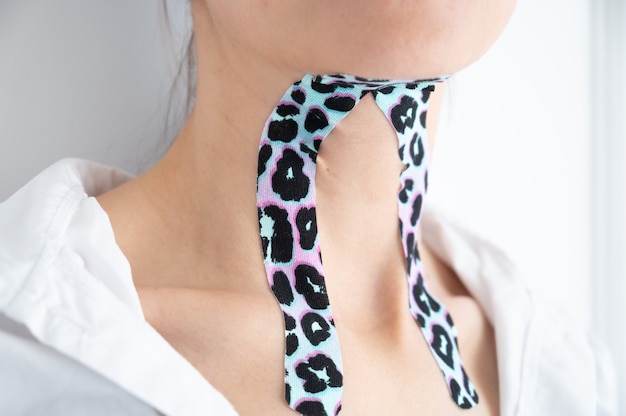 Close-up of young woman with colorful tapes on neck. Aesthetic taping. Lifting skin concept.