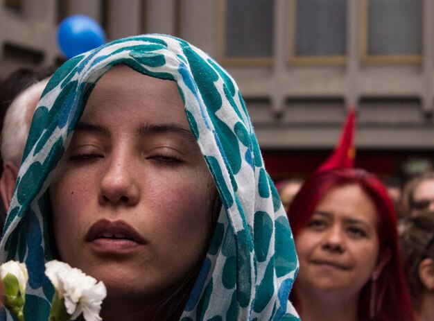 Foto close-up di una giovane donna con gli occhi chiusi che prega per strada