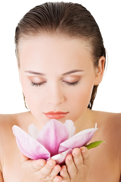 Close-up of young woman with eyes closed smelling flower against white background