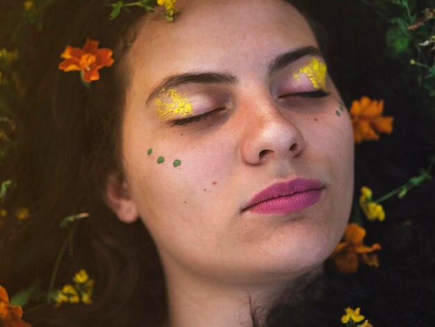 close-up of young woman with face paint and flowers on field
