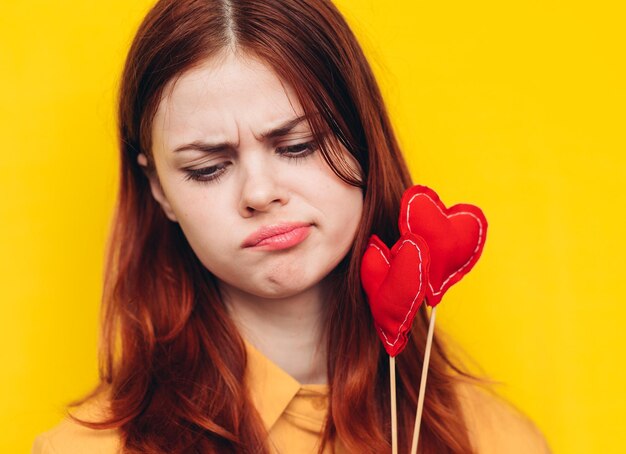 Close-up of young woman with red rose against yellow background