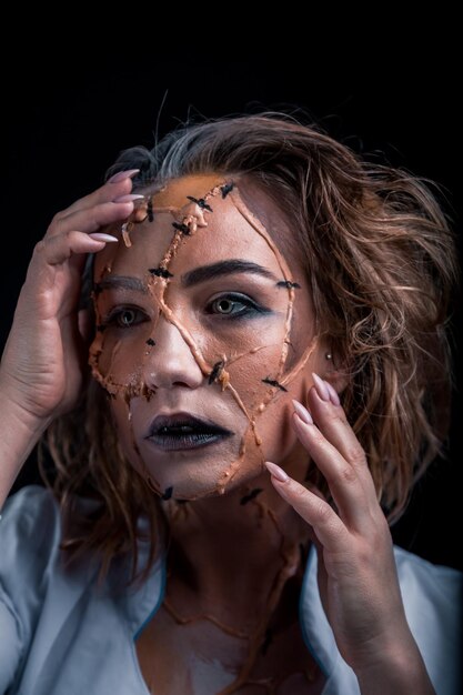 Foto close-up di una giovane donna con una faccia spaventosa dipinta su sfondo nero