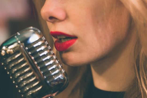 Foto close-up di una giovane donna con un microfono vintage