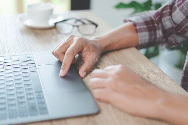 Close-up zakenman met een pen, smartphone en wijzend op financiële grafiek die bedrijfsrapport controleert op houten bureau met computerlaptop naast thuis. Stock foto