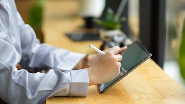 Close-up zakenvrouw in formele jurk zittend in coffeeshop met stylus pen om haar zakelijke ideeën op tabletcomputer te tekenen