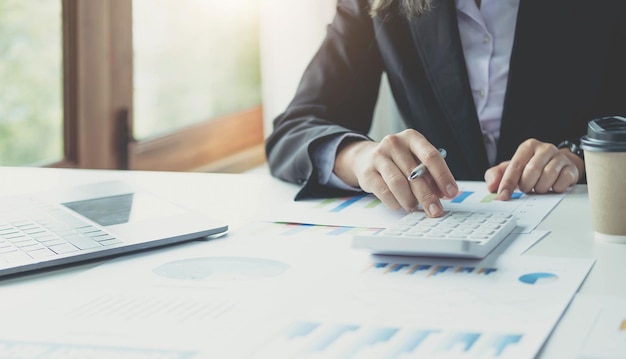 Close-up zakenvrouw met behulp van rekenmachine en laptop voor do math finance op houten bureau in kantoor en zakelijke achtergrond fiscale boekhoudkundige statistieken en analytisch onderzoek conceptxA