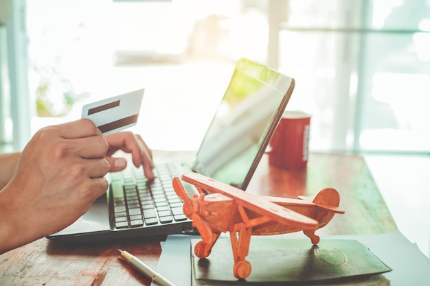 Close-up zijaanzicht shot van jonge zakenman werken op zijn laptop en met behulp van creditcard zit aan houten tafel in een koffiewinkel met vintage filter kleur toon