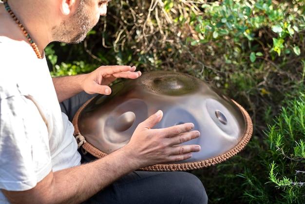 close-up zijaanzicht van de handen van een onherkenbare man die handpan spiritueel instrument bespeelt