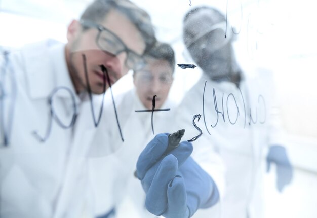 Close upa group of scientists recording the formula on a glass Board education and science